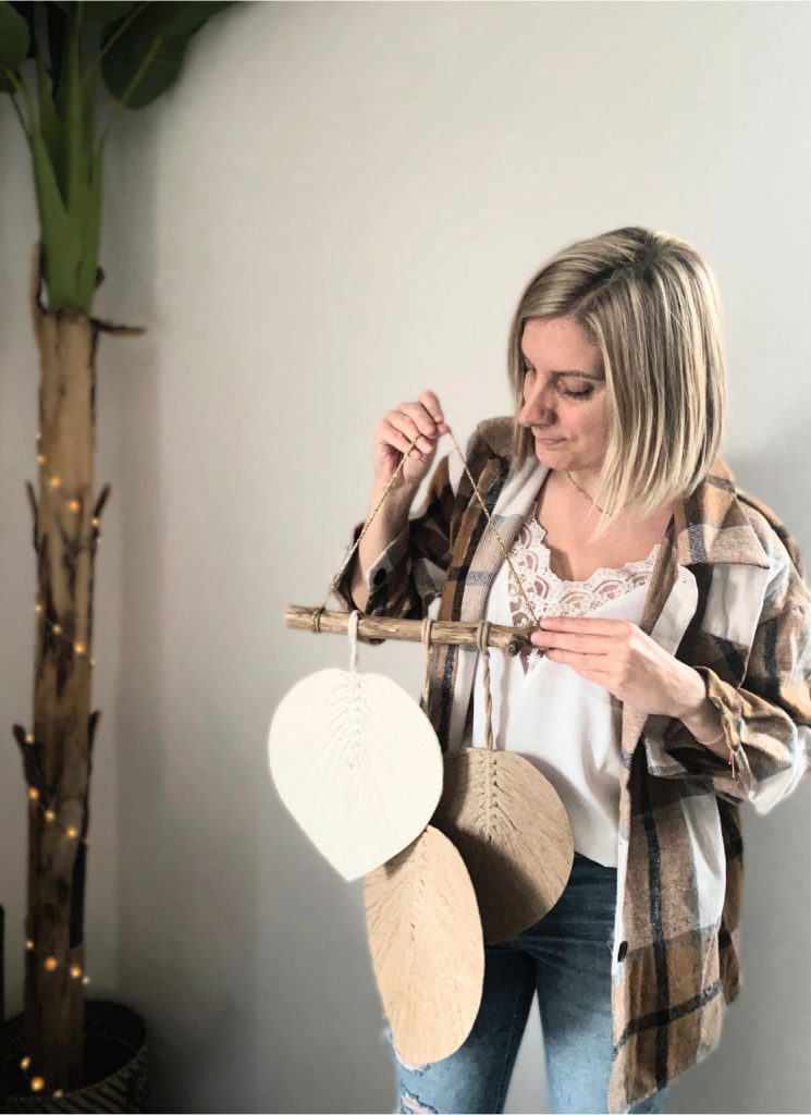 Artisane tenant une suspension murale en macramé aux tons naturels. Création personnalisée bohème