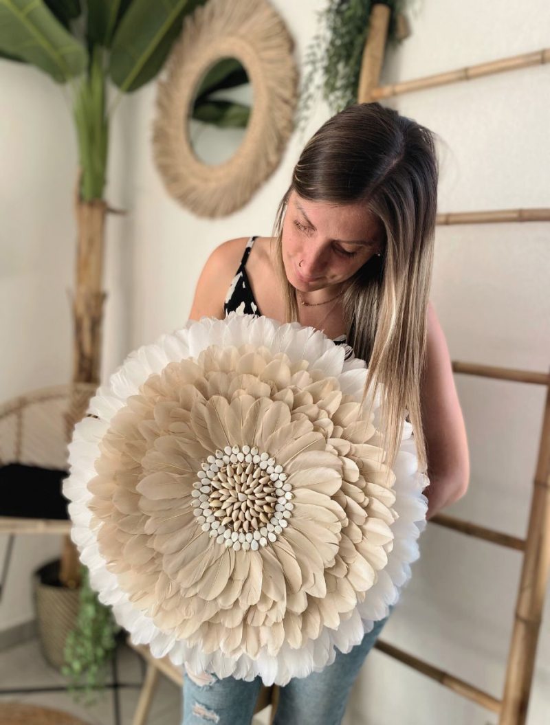 Créatrice présentant un Juju hat beige et blanc avec coquillages, décoration murale artisanale bohème