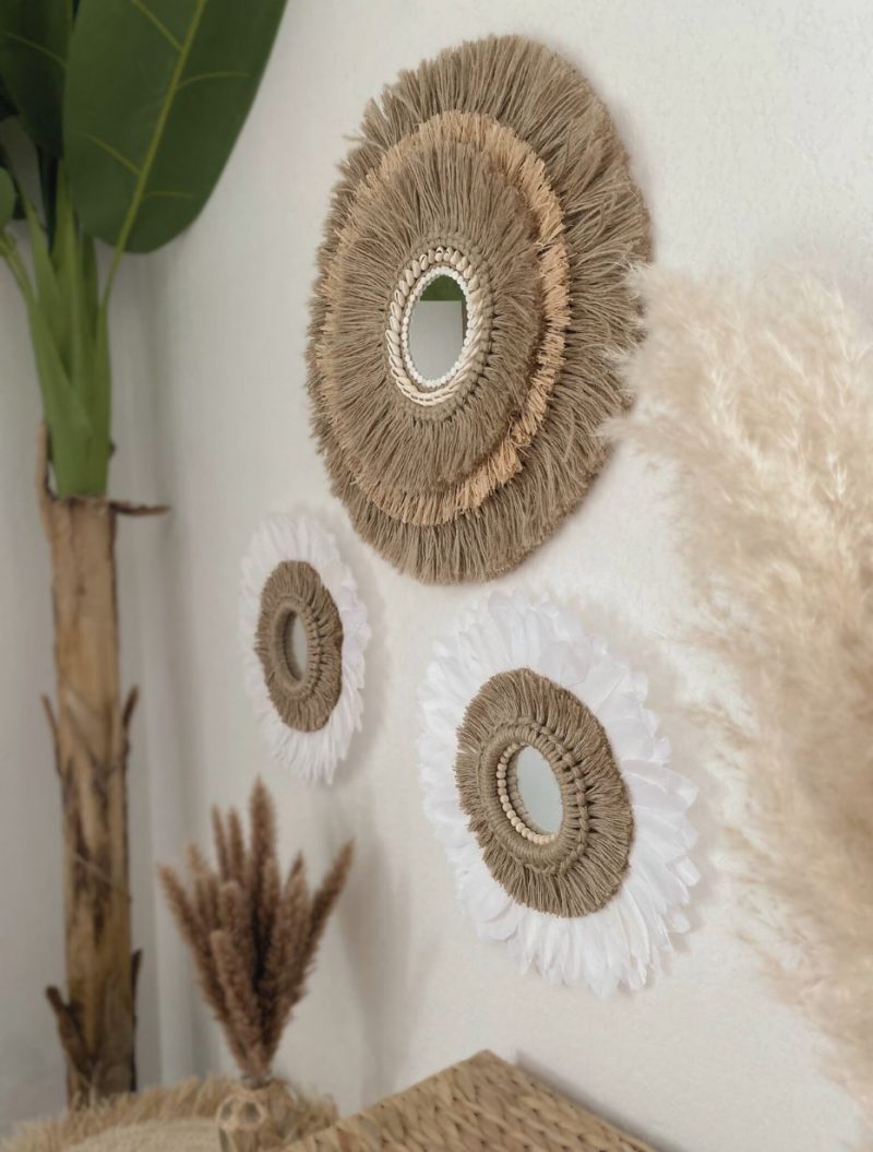 Trois miroirs muraux artisanaux en fibres naturelles et plumes blanches dans une décoration intérieure bohème