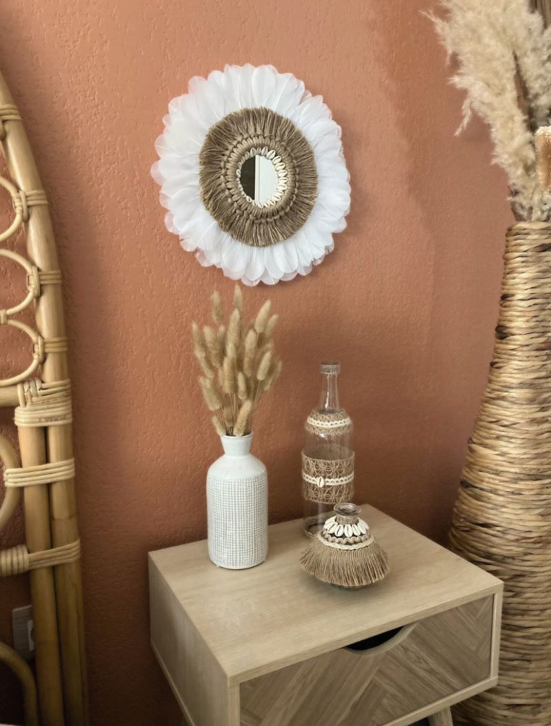 Décoration d’intérieur bohème avec miroir juju hat bohème et ses plumes blanches, corde naturelle et coquillages et vase et bouteille artisanale ornée de coquillages
