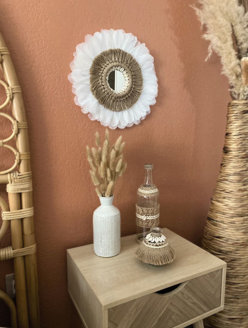 Décoration d’intérieur bohème avec miroir juju hat bohème et ses plumes blanches, corde naturelle et coquillages et vase et bouteille artisanale ornée de coquillages