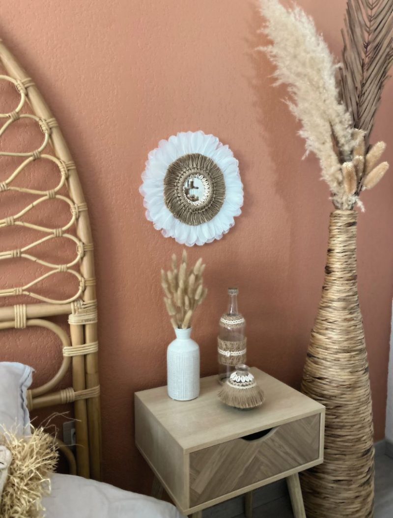 Décoration d’intérieur bohème avec miroir juju hat bohème et ses plumes blanches, corde naturelle et coquillages et vase et bouteille artisanale ornée de coquillages