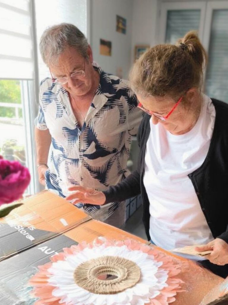 Cliente émue découvrant un miroir mural en plumes, offert pour la fête des mères